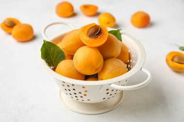 Colander full of ripe apricots on light background