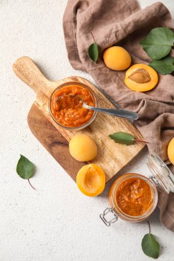 Composition with bowl of tasty apricot jam and fruits on light background