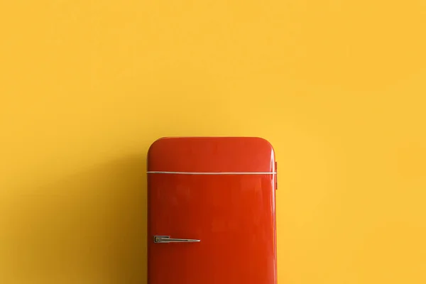 Stylish retro fridge near yellow wall