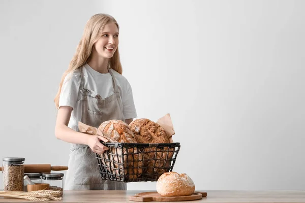 Young Woman Holding Basket Loaves Fresh Bread Light Background — Stock Photo, Image