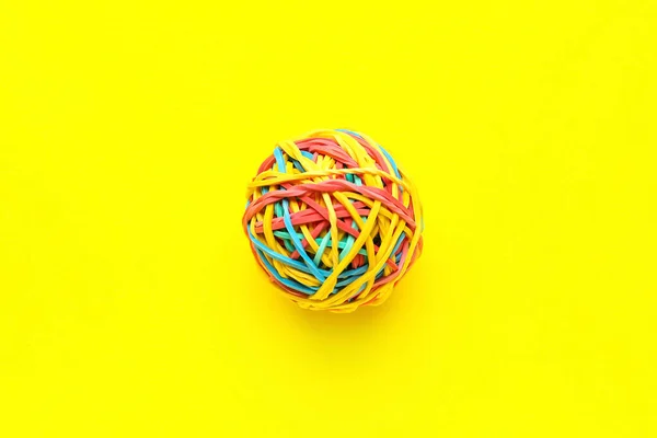 Colorful rubber band ball on yellow background