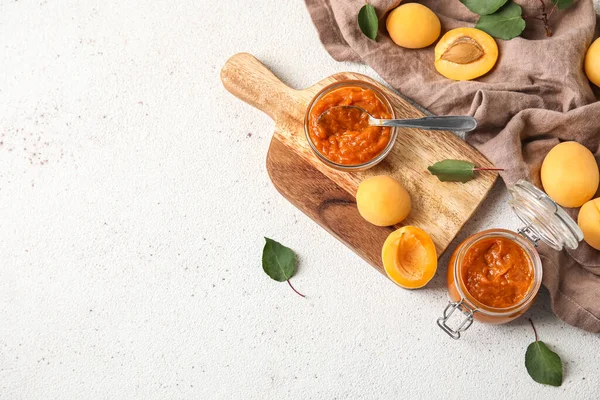 Composition with bowl of tasty apricot jam and fruits on light background