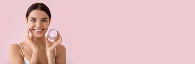 Beautiful young woman with cream on pink background with space for text