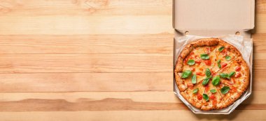 Cardboard box with delicious pizza Margarita on wooden background with space for text, top view