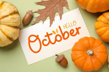 Card with text HELLO OCTOBER and autumn composition on green background