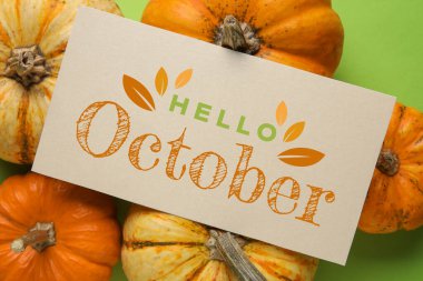 Card with text HELLO OCTOBER and autumn pumpkins on green background