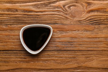 Bowl of soy sauce on wooden background