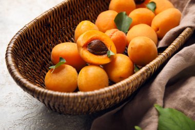 Basket with ripe apricots on table, closeup