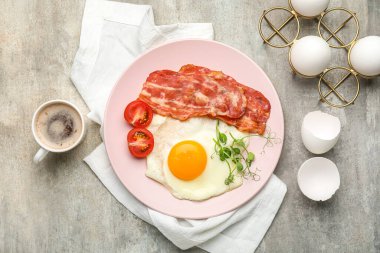 Plate with tasty fried egg, bacon and cup of coffee on grunge background