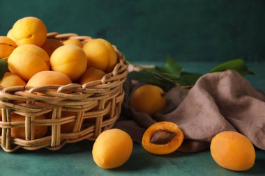 Wicker basket of ripe apricots on color background, closeup