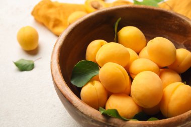 Bowl of ripe apricots on light background, closeup