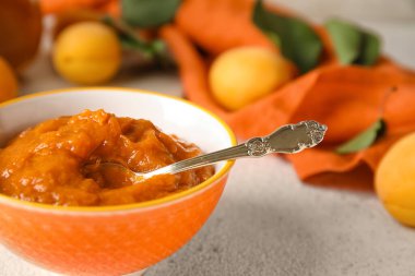 Bowl of sweet apricot jam on light table, closeup
