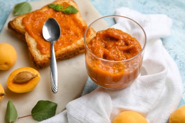 Glass of tasty apricot jam on table, closeup