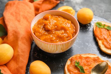 Bowl of sweet apricot jam on table, closeup