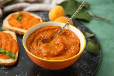 Bowl of sweet apricot jam on table, closeup