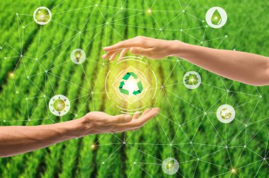 Female and male hands with digital icons and recycling symbol on blurred green background. Concept of green technology