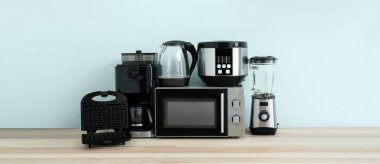 Different household appliances on table against light background 