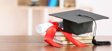Graduation hat, diploma and books on table