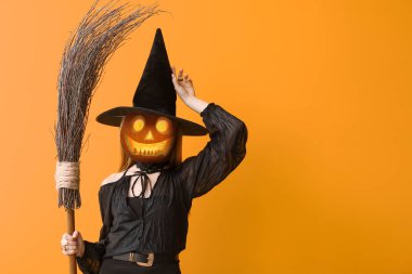 Witch with Halloween pumpkin instead of her head on orange background