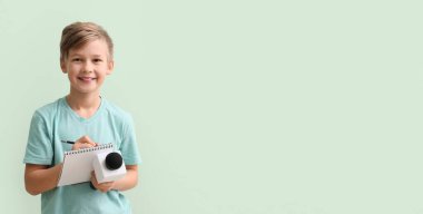 Little journalist with microphone and notebook on light color background with space for text