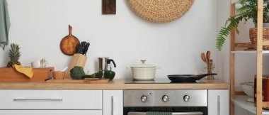 Modern electric stove with cookware and utensils in light kitchen