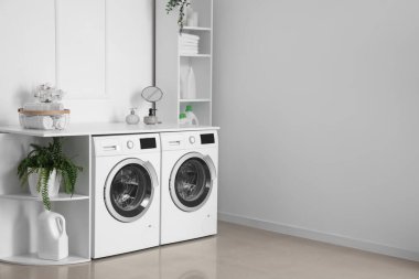 Interior of light laundry room with washing machines and shelving units