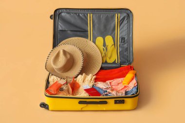 Open suitcase with clothes, passport and ticket on color background