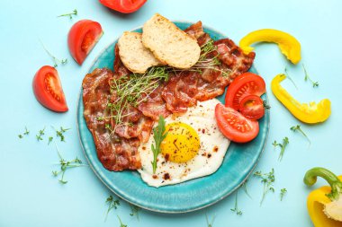 Composition with tasty fried egg, bacon and vegetables on color background