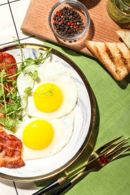 Plate of tasty fried eggs with bacon on table, closeup