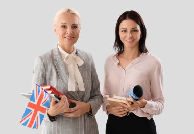Female teachers with UK flag and books on light background