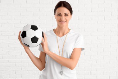 Beautiful PE teacher with ball on white brick background