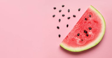 Slice of tasty watermelon and seeds on pink background with space for text