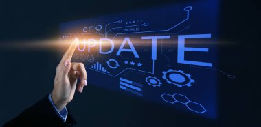 Woman using virtual screen with word UPDATE on dark background