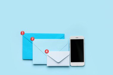 Paper envelopes with new unread messages and mobile phone on blue background