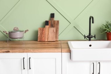 Counters with cutting boards and sink near green wall