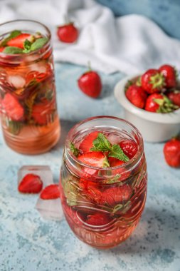 Glass of strawberry lemonade on blue background, closeup