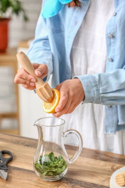 Woman squeezing lemon juice into jug in kitchen