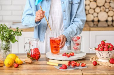 Mutfakta soğuk çilekli limonata içen bir kadın.