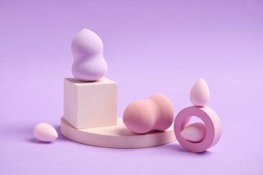 Makeup sponges with decor on violet background