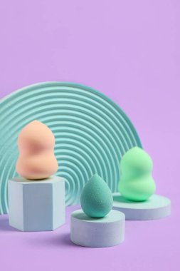 Makeup sponges with decor on violet background