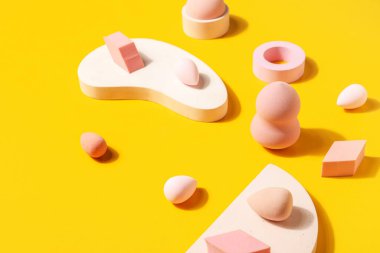 Makeup sponges with decor on yellow background