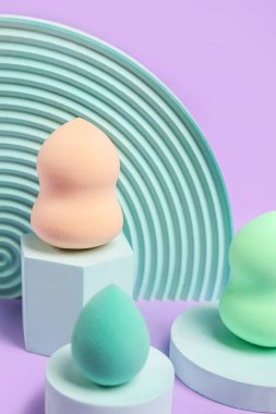 Makeup sponges with decor on violet background