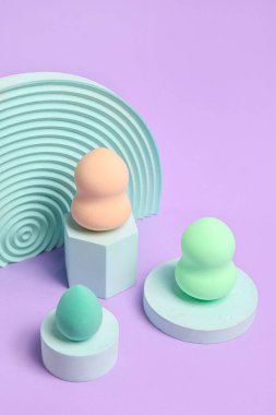Makeup sponges with decor on violet background
