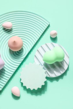 Stands with makeup sponges on green background