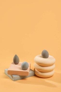 Grey makeup sponges with decor on beige background