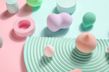 Makeup sponges with decor on pink and blue background