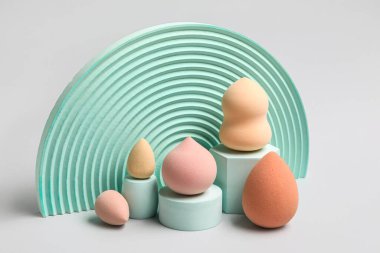 Beige makeup sponges with decor on grey background