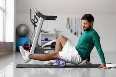 Young man training with foam roller in gym