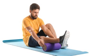 Young man training with foam roller on white background
