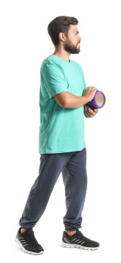 Young man with foam roller on white background